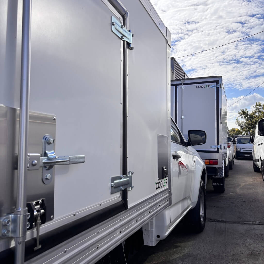 Refrigerate Ute box parked next to other work vehicles | Featured image for the Refrigerated Ute Box page by Cooler.